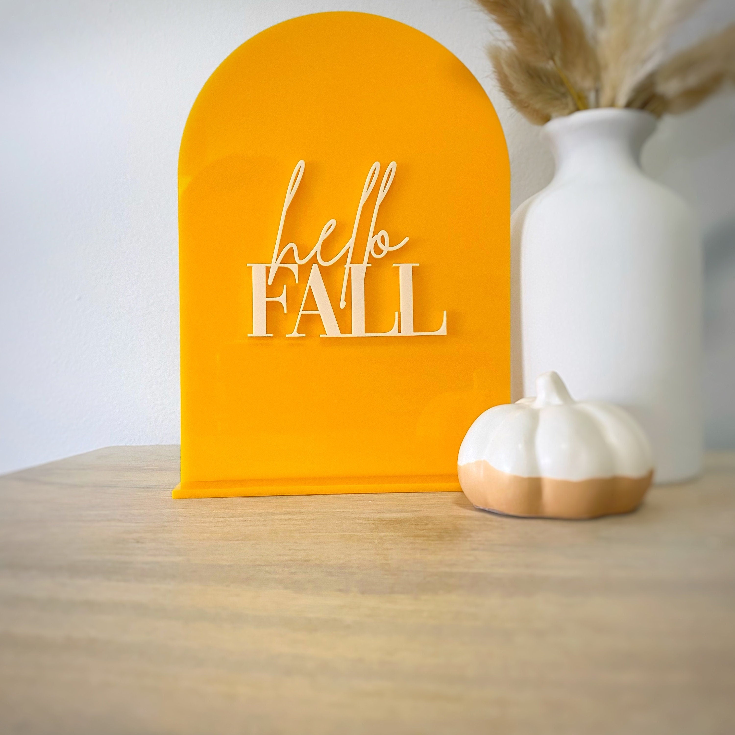 Orange yellow acrylic table sign that reads hello Fall in cream letters 